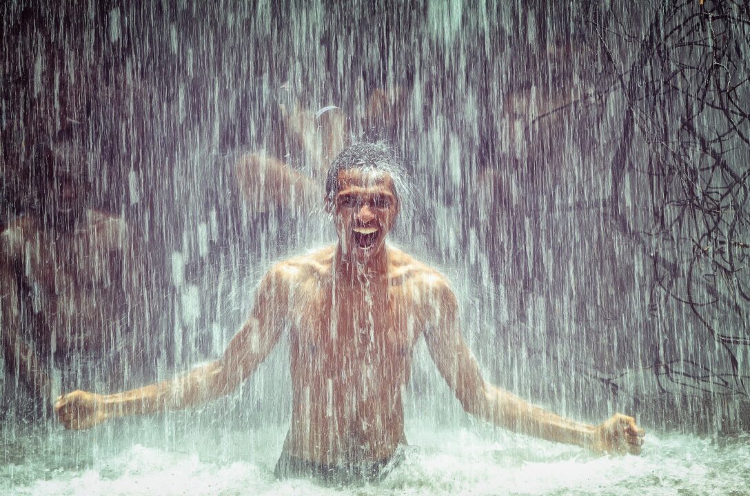 man-under-waterfall